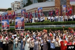People wave to the motorcade carrying North Korean leader Kim Jong Un and Russian President Vladimir Putin during a welcoming ceremony at Kim Il Sung Square in Pyongyang on June 19, 2024. (Sputnik via AFP)