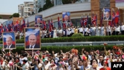 In this pool photograph distributed by the Russian state agency Sputnik, people wave to the motorcade carrying North Korea's leader Kim Jong Un and Russian President Vladimir Putin during a welcoming ceremony at Kim Il Sung Square in Pyongyang.