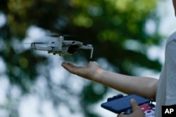 Andriy Pokrasa, 15, lands his drone on his hand during an interview with The Associated Press in Kyiv, Ukraine, Saturday, June 11, 2022. (AP Photo/Natacha Pisarenko)