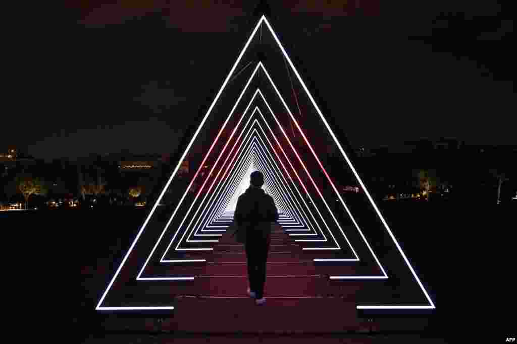 A man walks through a Christmas illuminated sculpture at the Stavros Niarhos cultural center in Athens, Greece.