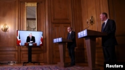 From left, Britain's Prime Minister Boris Johnson, Chief Medical Officer for England Chris Whitty, and Director of the Oxford Vaccine Group Andrew Pollard attend a virtual news conference on the COVID-19 situation at Downing Street, London, Nov. 23, 2020.