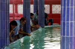 FILE - Muslims perform ablution as they gather to attend Friday prayer amid an outbreak of the coronavirus disease, at a mosque in Karachi, Pakistan, March 20, 2020.