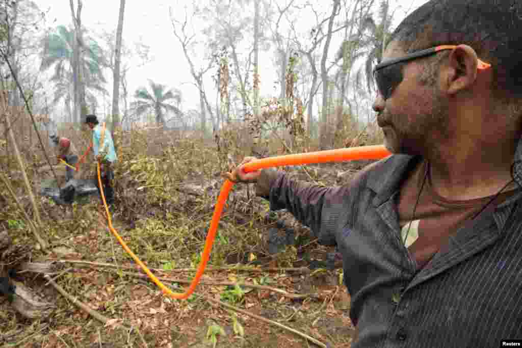 Miembros de la comunidad local trabajan para enfriar el suelo después de un incendio forestal en Río Blanco, Bolivia. (REUTERS)