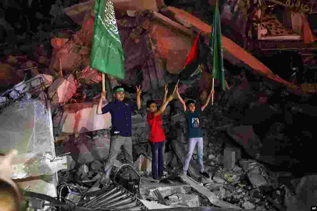 Palestinian children wave green flags as they stand on the rubble of a destroyed building while celebrating the cease-fire agreement between Israel and Hamas in Gaza City.