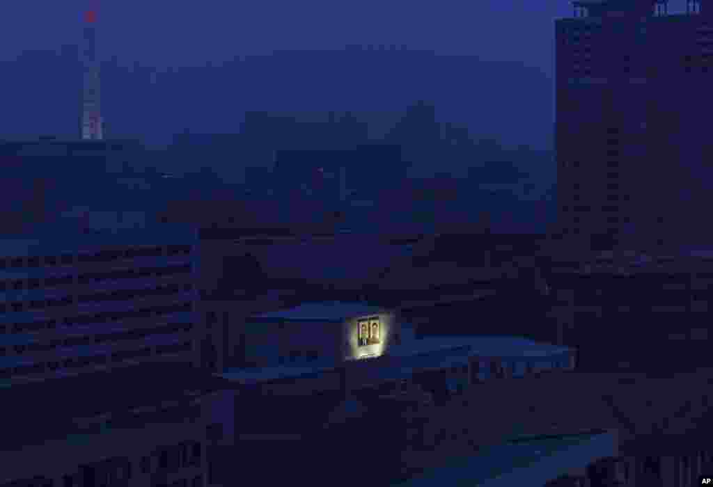 북한 평양의 밤. 김일성 주석과 김정일 국방위원장의 대형 초상화에만 조명을 비추고 있다. 멀리 주체사상탑이 보인다.