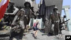 Residentes de Varsovia observan el monumento al Levantamiento de Varsovia de 1944 contra la ocupación nazi, en el que murieron unos 18.000 combatientes de la resistencia y 180.000 civiles, en Varsovia, Polonia, el miércoles, 1 de agosto de 2018.