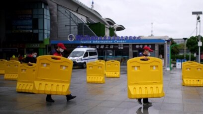 Nhân viên dời các rào chắn đường trước trạm xe lửa Vũ Hán vào ngày đầu tiên dịch vụ xe lửa vào thành phố được nối lại sau hai tháng phong tỏa vì dịch virus corona, vốn bùng phát đầu tiên ở đây, ngày 28 tháng 3, 2020.