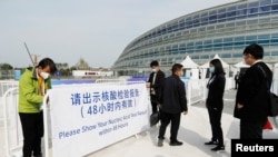 2021年10月8日，在中国国家速滑馆举行的冬奥会测试赛门外，工作人员引导人们出示新冠核酸检测结果。