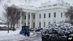 A plow removes snow from the White House driveway after a winter storm, on Tuesday, Feb. 17, 2015, in Washington. 