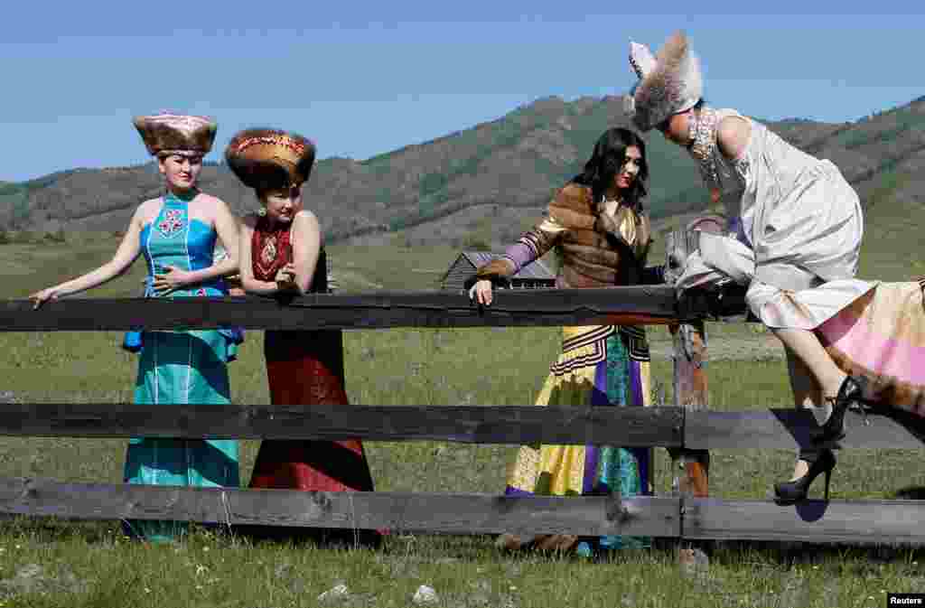 A model from the "Altyr" fashion theater, dressed in the Khakas national costume, climbs over a wooden fence during a photo session, as a part of the rehearsal for the Tun-Pairam traditional holiday (The Holiday of the First Milk) celebration at a museum preserve outside Kazanovka village near Abakan in the Republic of Khakassia, Russia.