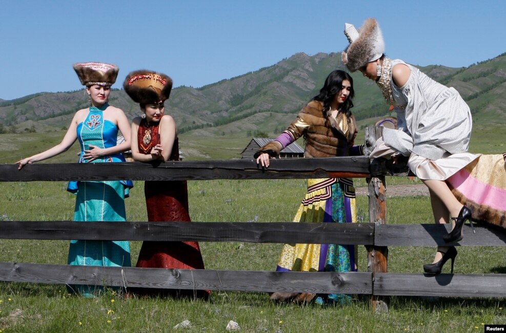A model of the &quot;Altyr&quot; fashion theater, dressed in Khakas national costumes, get over a wooden fence during a photo session, as a part of the rehearsal for the Tun-Pairam traditional holiday (The Holiday of the First Milk) celebration at a museum preserve&nbsp;outside Kazanovka village near Abakan in the Republic of Khakassia, Russia.