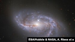 Looking deep into the Universe, the NASA/ESA Hubble Space Telescope catches a passing glimpse of the numerous arm-like structures that sweep around this barred spiral galaxy, known as NGC 2608. (Image: ESA/Hubble & NASA, A. Riess et al.)