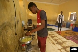 FILE - A man cooks a meal of instant noodles on a makeshift stove in a classroom at a school that has been transformed into a shelter for people displaced by conflict in Sudan's northern border town of Wadi Halfa near Egypt on September 11, 2023.