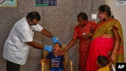 A health worker takes a mouth swab sample of a boy to test for COVID-19 in Hyderabad, India, April 29, 2021.