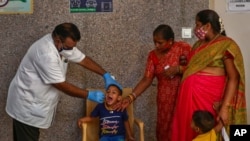 A health worker takes a mouth swab sample of a boy to test for COVID-19 in Hyderabad, India, Thursday, April 29, 2021. (AP Photo/Mahesh Kumar A.)