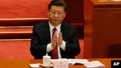 ຮູບໃນວັນທີ 9 ມີນາ 2018, ​​​​ປະທານ​ປະ​ເທດ​ຈີນ ທ່ານ ສີ ຈິ້ນຜິງ (Xi Jinping) ຕົບມືສະໜັບສະໜຸນ ປະທານໄອຍະການ ທ່ານ ກາວ ຈຽນມິ້ງ (Cao Jianming) ໃນກອງປະຊຸມ ຄົບຄະນະ ສະພາປະຊາຊົນ ແຫ່ງຊາດ ໃນປັກກິ່ງ. 