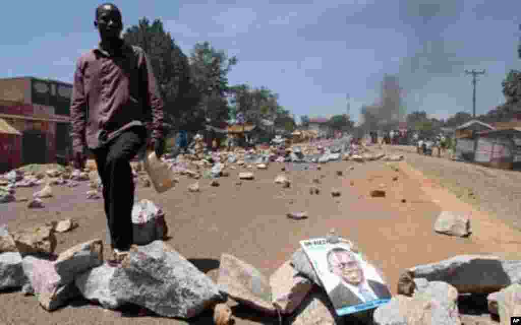 A supporter of Uganda's Forum for Democratic Change (FDC) leader Kizza Besigye stands on the road blocked by stones during a protest in the Kasangati suburb of the capital Kampala, April 14, 2011. Ugandan police fired teargas to disperse a crowd that gath