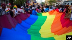 FILE - People carry a giant pride flag during the annual LGBT Parade in Havana, Cuba, May 12, 2018. The #MeQueer hashtag has gone viral since it was first used August 13, with LGBT people tweeting about their experiences of verbal and physical abuse.