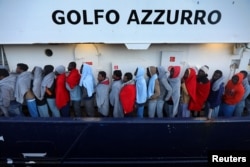 FILE - Migrants line up as they wait to be processed by Italian authorities aboard the former fishing trawler Golfo Azzurro moored in the port of Augusta following their rescue by Spanish NGO Proactiva Open Arms from their drifting dinghies off the Libyan coast in central Mediterranean Sea, April 2, 2017.