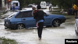 A local resident walks with her child through a flooded street in the southern Russian town of Krymsk July 7, 2012.