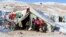 FILE - Syrian refugees sit by their tent in a Syrian refugee camp on the Lebanese border town of Arsal, in the eastern Bekaa on December 15, 2013. 
