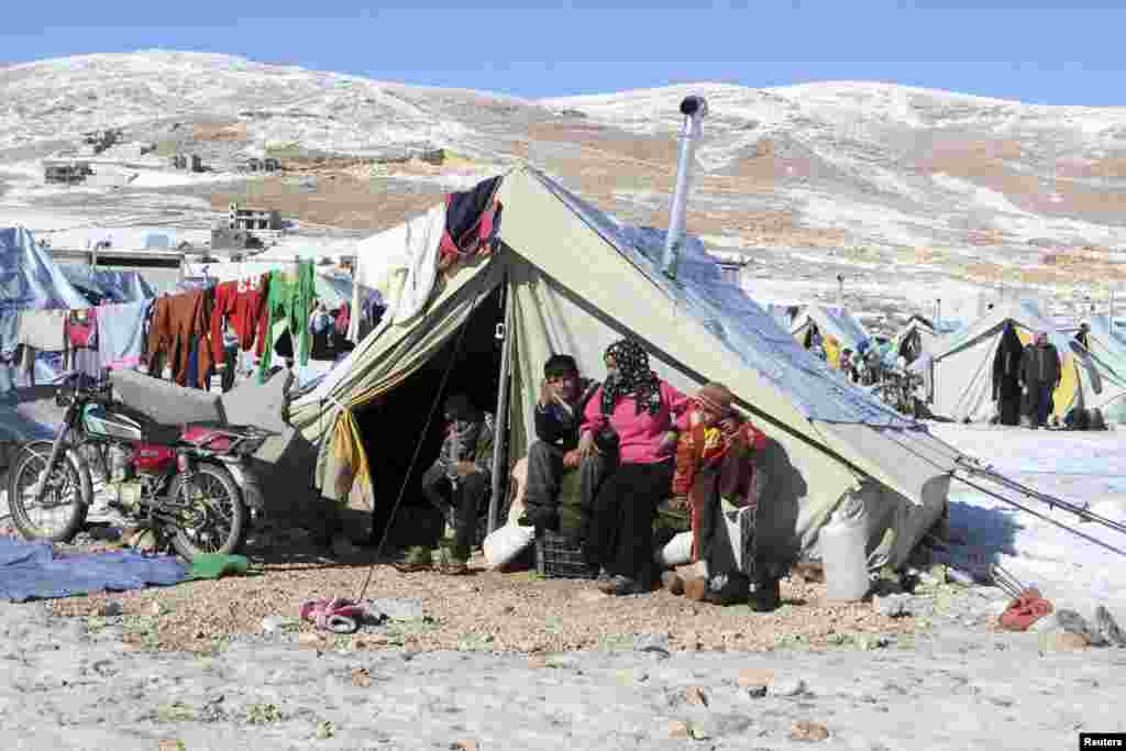 Syrian refugees sit by their tent in a camp on the Lebanese border town of Arsal, Dec. 15, 2013