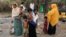 A family stands beside remains of a market which was set on fire, in Rohingya village outside Maungdaw, in Rakhine state, Myanmar, Oct. 27, 2016. 