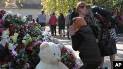 A woman prays near a memorial to the people killed during an attack in the vocational college in Kerch, Crimea, Oct. 18, 2018. 