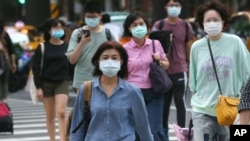 FILE - People wearing face masks to protect against the spread of the coronavirus cross and intersection in Taipei, Taiwan, Nov. 20, 2020. 