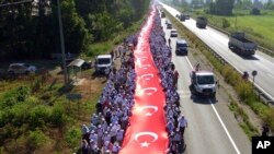 Ribuan pendukung memegang bendera nasional sepanjang 1.100 meter saat mengikuti Kemal Kilicdaroglu,pemimpin oposisi utama Turkey, Partai Rakyat Republik pada hari ke-17 pawai 425 kilometer di Sakarya, 220 kilometer dari ibukota Ankara, Turki, 1 Juli 2017. (Foto: dok).