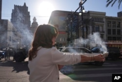 Stephanie Drake membakar pohon sage di Canal dan Bourbon Street, Kamis, 2 Januari 2025 di New Orleans. (George Walker IV/AP)