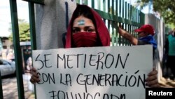 Una estudiante universitaria enmascarada porta un rótulo de protesta en momentos en que la Policía mantiene su persecución contra quienes han hecho oposición al gobierno de Daniel Ortega. [Foto: Reuters]