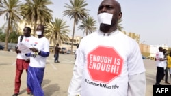 People with a white paper covering their mouth and a t-shirt reading "enough is enough" demonstrate in Dakar on April 22, 2016, against the alleged human rights violations in Gambia.
