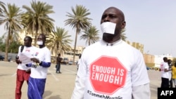 FILE - People with a white paper covering their mouth and a t-shirt reading "enough is enough" demonstrate in Dakar on April 22, 2016, against the alleged human rights violations in Gambia.