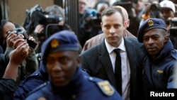 ARCHIVO - Oscar Pistorius es escoltado por policías para oir su sentencia el 2013 por el asesinato de su novia Reeva Steenkamp.