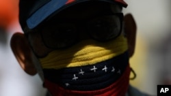 Un manifestante, con una mascarilla protectora tejida a mano con los colores representativos de la bandera nacional venezolana, asiste a una marcha exigiendo una distribución más equitativa y rápida de las vacunas COVID-19, en Caracas,17 de abril de 2021.