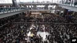 Protesters surround banners that read "Those charge to the street on today is brave!," center top, and "Release all the detainees!" during a sit-in rally at the arrival hall of the Hong Kong International airport in Hong Kong, Monday, Aug. 12, 2019…