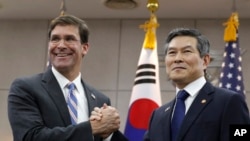 US Defense Secretary Mark Esper, left, and South Korean Defense Minister Jeong Kyeong-doo, right, clasp hands ahead of a meeting at Defense Ministry in Seoul, South Korea, Aug. 9, 2019.
