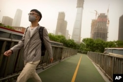 A man wears a face mask as he walks across a pedestrian bridge during a dust and sand storm in Beijing, May 4, 2017.