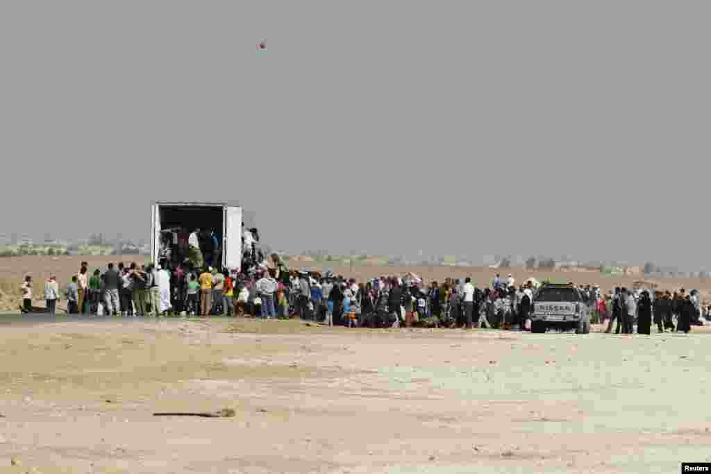 Para pengungsi Suriah antre masuk ke truk yang akan membawa mereka dari kamp pengungsi Al-Zaatri di Mafraq, Yordania, ke kampung halaman di Suriah (30/7). (Reuters/Muhammad Hamed)