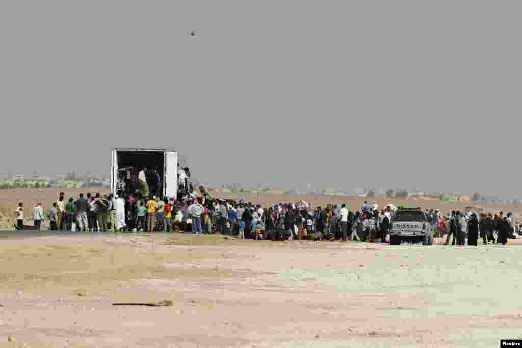 Syrians refugees try to enter a truck which will transport them back to their homeland at the Al-Zaatri refugee camp in the Jordanian city of Mafraq, near the border with Syria, July 30, 2013.