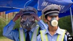 Chinese traffic police wear masks as they man a security checkpoint near the site of an explosion in northeastern China's Tianjin municipality, Aug. 15, 2015.