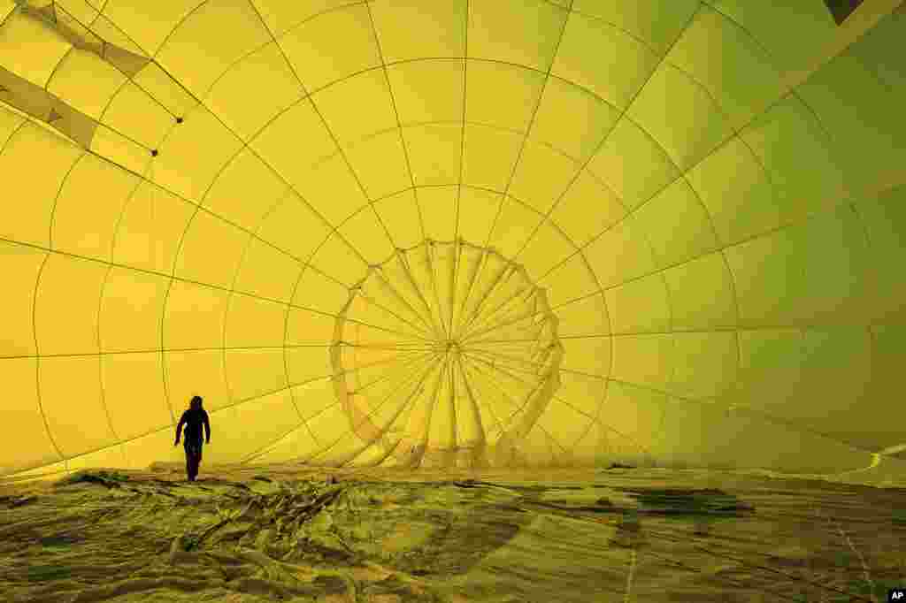 A hot air balloon pilot checks her rigging inside the canopy before climbing, with 43 balloon teams taking part, for a Fiesta Flypast over the city of Bristol, Britain, as part of the socially distanced version of the Bristol International Balloon Fiesta.