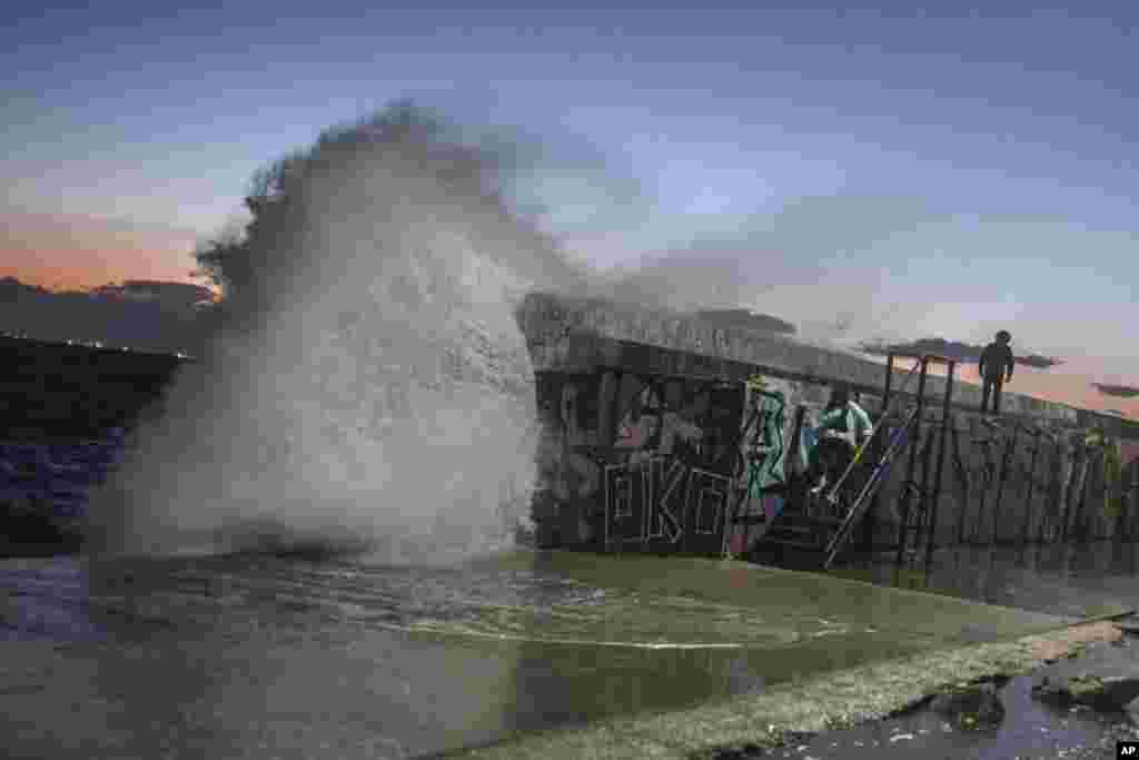 A wave hits a wave-lashed breakwater during a windy afternoon in the southern Athens coastal suburb of Flisvos, Greece, Feb. 8, 2021.