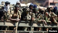 Members of the military gesture to the photographer as they patrol the streets of the capital Harare, Zimbabwe, Aug. 2, 2018. 