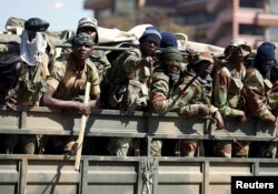 Members of the military gesture to the photographer as they patrol the streets of the capital Harare, Zimbabwe, Aug. 2, 2018.