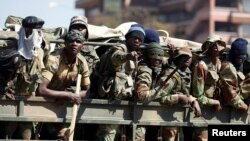 FILE: Members of the military gesture to the photographer as they patrol the streets of the capital Harare, Zimbabwe, Aug. 2, 2018. 