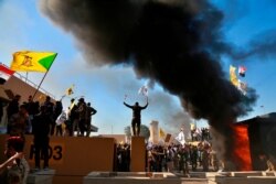 Protesters burn property in front of the U.S. embassy compound, in Baghdad, Iraq, Dec. 31, 2019.