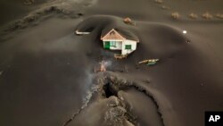 A fissure is seen next to a house covered with ash on the Canary island of La Palma, Spain.
