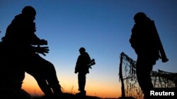 Ukrainian soldiers man a military check point by a camp on a field the Ukrainian Army forces set up close to the Russian border in east Ukraine, March 21, 2014.